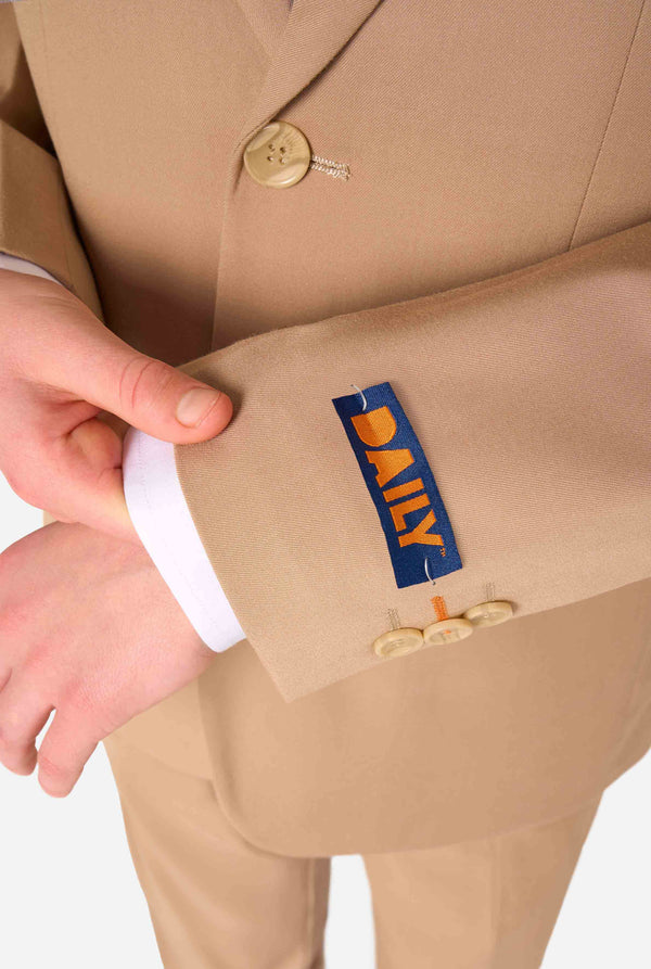 Teenager in einem stylischen hellbraun-beigen Anzug mit weißem Hemd blickt selbstbewusst in die Kamera. Perfektes formelles Outfit für besondere Anlässe, Hochzeiten und Partys. Ärmel in Nahaufnahme.