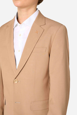 Teenager in einem stylischen hellbraun-beigen Anzug mit weißem Hemd blickt selbstbewusst in die Kamera. Perfektes formelles Outfit für besondere Anlässe, Hochzeiten und Partys. Brust-Nahaufnahme.