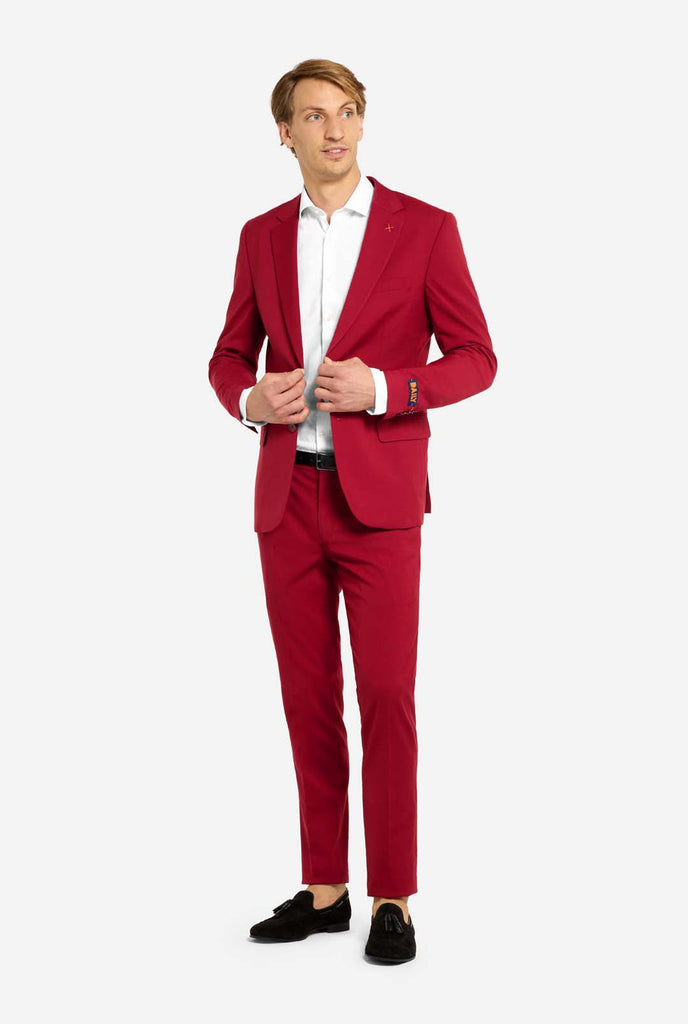 Bild mit hellgrauem Hintergrund und Mann trägt Bright Burgundy Herrenanzug und weißes Hemd. Der Anzug besteht aus Blazer und Hose. Ganzkörperbild.