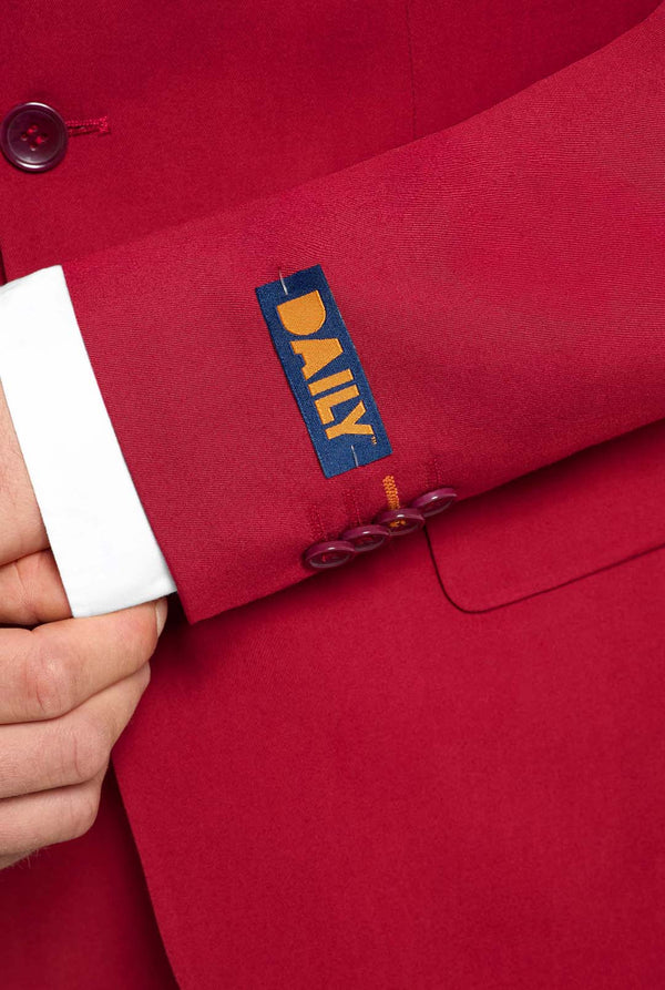 Bild mit hellgrauem Hintergrund und Mann trägt Bright Burgundy Herrenanzug und weißes Hemd. Anzüge besteht aus Blazer und Hose. Konzentriert sich auf die Ärmel.