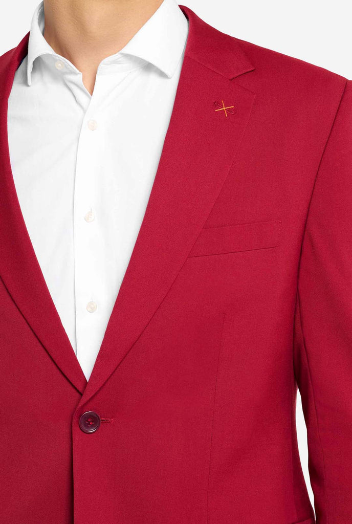 Bild mit hellgrauem Hintergrund und Mann trägt Bright Burgundy Herrenanzug und weißes Hemd. Anzüge besteht aus Blazer und Hose. Konzentriert sich auf die Brust.