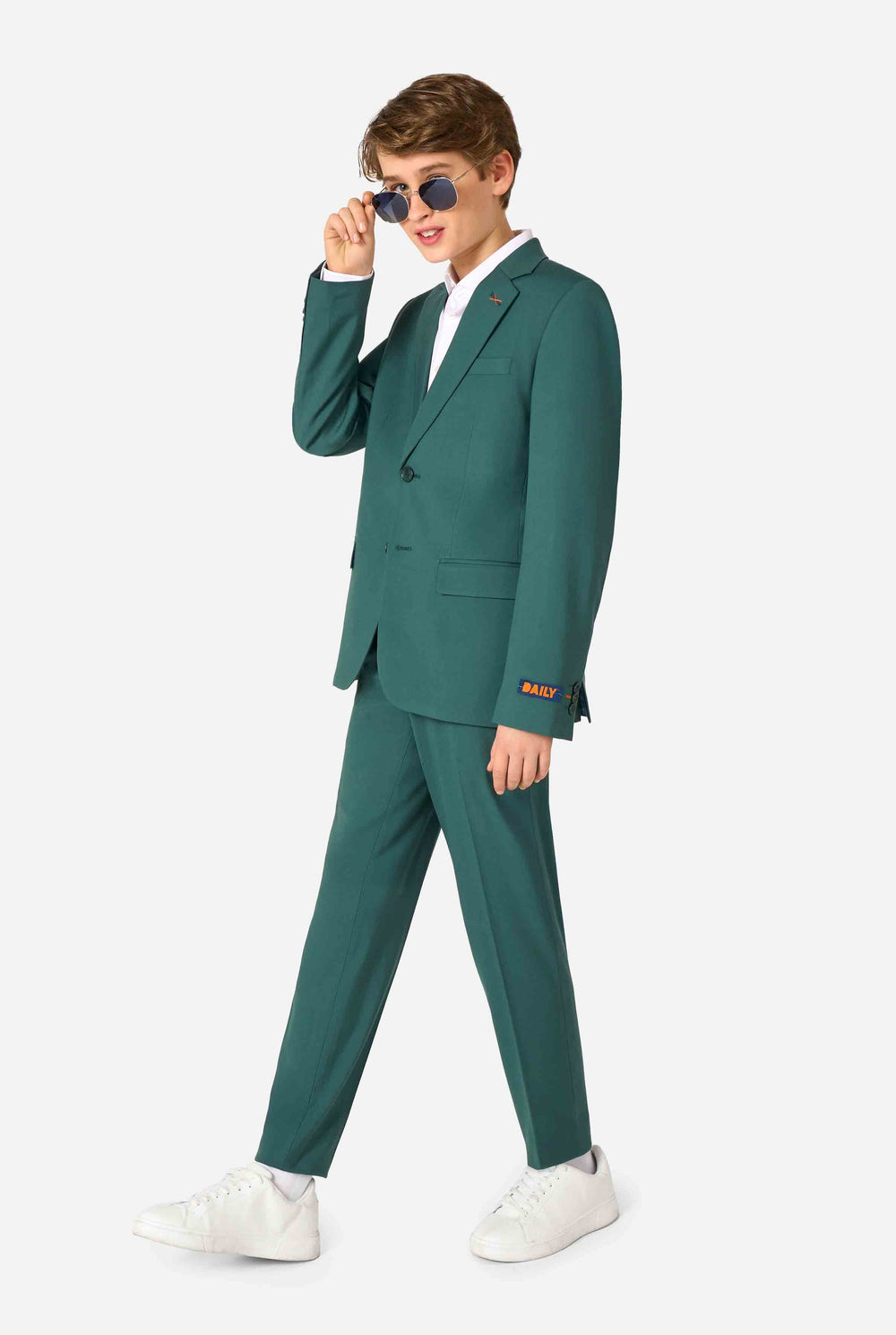 Teenager in einem eleganten dunkelgrünen Anzug mit weißem Hemd und selbstbewusstem Lächeln. Perfektes formelles Outfit für besondere Anlässe, Hochzeiten und Partys.