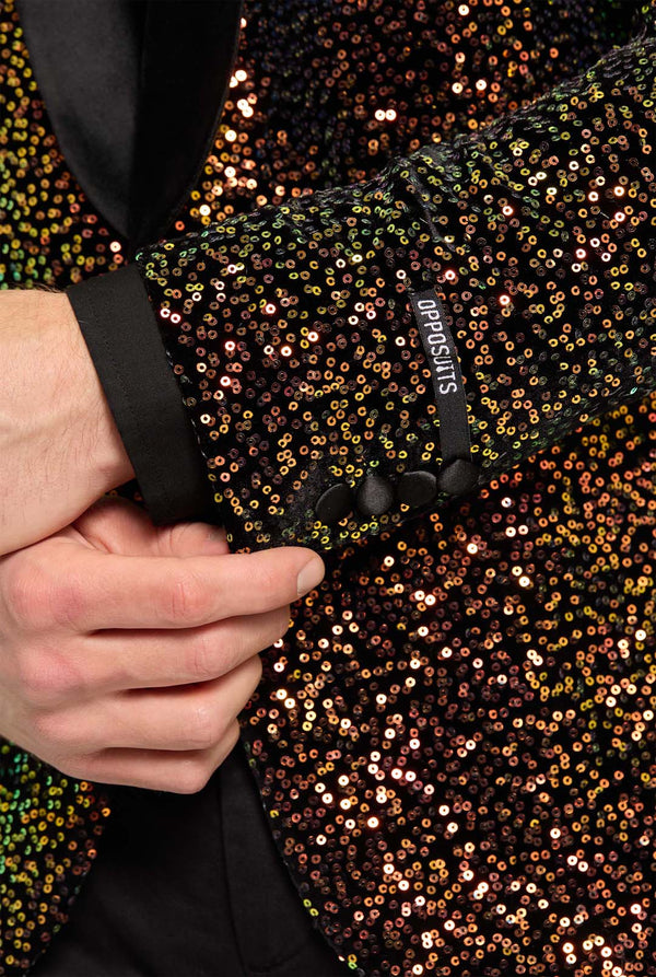 Dieses Bild zeigt eine stilvolle Herren-Dinnerjacke aus der OppoSuits Deluxe Kollektion, verziert mit schillernden bernsteinfarbenen Pailletten, die einen funkelnden Effekt erzeugen. Der Paillettenblazer verfügt über ein elegantes Satin-Revers und eine maßgeschneiderte Passform. Das Modell kombiniert die Jacke mit einem klassischen schwarzen Hemd und einer Fliege. Perfekt geeignet für formelle Anlässe, Festtagsfeiern oder Silvester. Nahaufnahme des Ärmels.