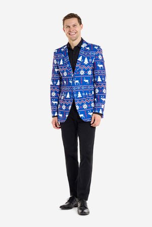 Mann trägt einen blauen Weihnachtsblazer mit nordischen Weihnachtsmotiven. Außerdem trägt er eine schwarze Hose und ein schwarzes Hemd. Ganzkörperfoto.