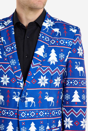 Mann trägt einen blauen Weihnachtsblazer für Männer mit nordischen Weihnachtsfiguren. Er trägt außerdem eine schwarze Hose und ein schwarzes Herrenhemd. Nahaufnahme der Brust.