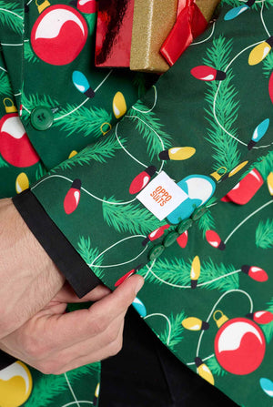 Mann trägt einen grünen Weihnachtsblazer für Herren mit verziertem Weihnachtsbaum-Aufdruck. Er trägt außerdem eine schwarze Hose und ein schwarzes Herrenhemd. Nahaufnahme des Ärmels.