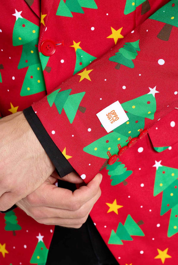 Mann trägt einen roten Weihnachtsblazer für Herren mit Weihnachtsbäumen und Sternen. Er trägt außerdem eine schwarze Hose und ein schwarzes Herrenhemd. Nahaufnahme der Ärmel.