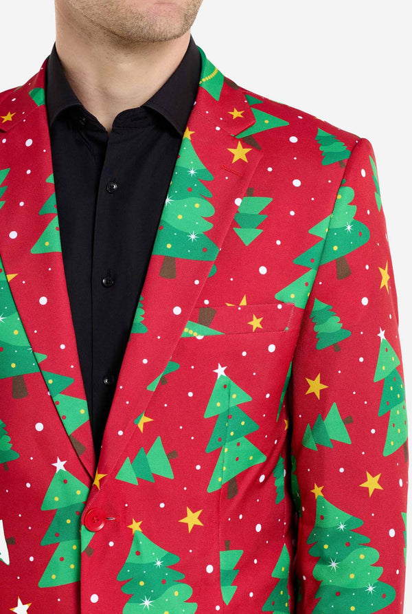 Mann trägt einen roten Weihnachtsblazer für Herren mit Weihnachtsbäumen und Sternen. Er trägt außerdem eine schwarze Hose und ein schwarzes Herrenhemd. Nahaufnahme der Brust.