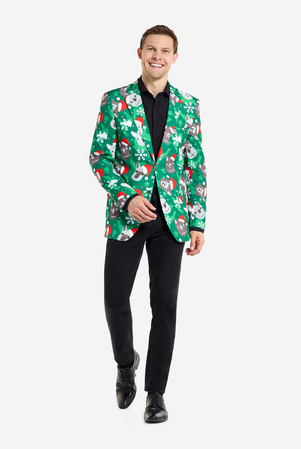 Mann trägt einen grünen Weihnachtsblazer für Männer mit Weihnachtslamas. Der Mann trägt außerdem eine schwarze Hose und ein schwarzes Herrenhemd. Ganzkörperbild.