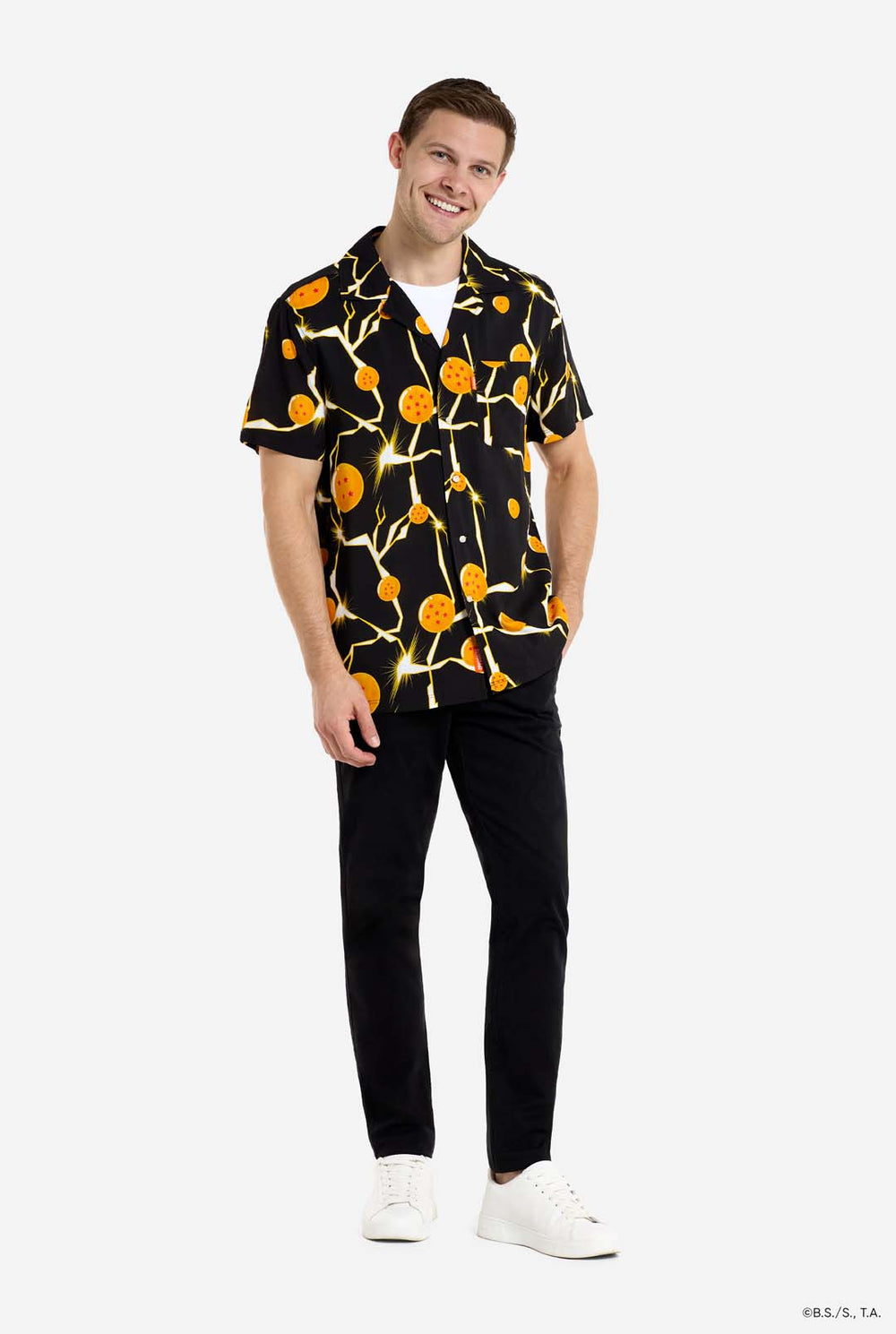 Mann trägt ein schwarzes Hawaiihemd mit Dragon Ball Z-Aufdruck, auf dem Dragon Balls und Lichter zu sehen sind. Außerdem trägt er ein weißes T-Shirt und eine schwarze Hose.