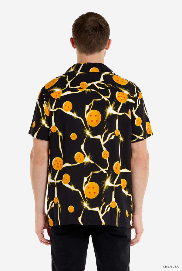 Mann trägt ein schwarzes Hawaiihemd mit Dragon Ball Z-Aufdruck, auf dem Dragon Balls und Lichter zu sehen sind. 
