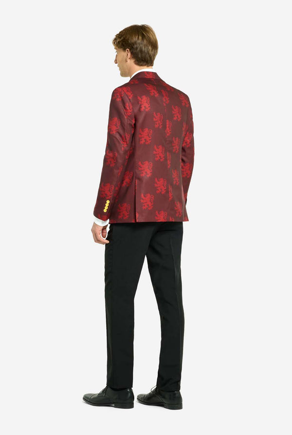 Bild mit hellgrauem Hintergrund und einem Mann, der einen Harry-Potter-Anzug im Gryffindor-Stil trägt. Der Anzug besteht aus einem roten Blazer mit Gryffindor-Logo und hellroten Löwen-Allover-Print, schwarzen Hosen und einer rot-gelb diagonal gestreiften Krawatte. Der Mann zeigt die Rückansicht des Anzugs.