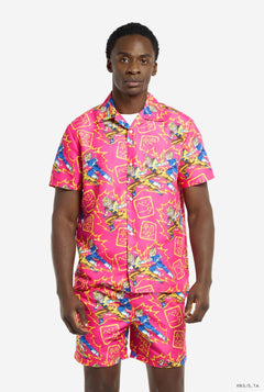 Image of man wearing a pink summer set with a Dragon Ball Z print. Print shows supercharged Goku and Vegeta fighting and some Japanese symbols in yellow. Summer set consists of short sleeve shirt and shorts.
