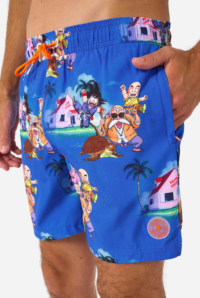 Blaue Badeshorts für Herren mit Dragon Ball-Motiv mit Goku, Krillin, Master Roshi und anderen Charakteren von Kame House. Perfekt für Anime-Fans am Strand oder Pool.