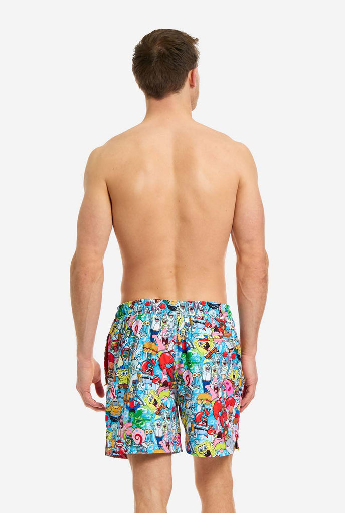 Man wearing swim trunks with SpongeBob print, view from the back