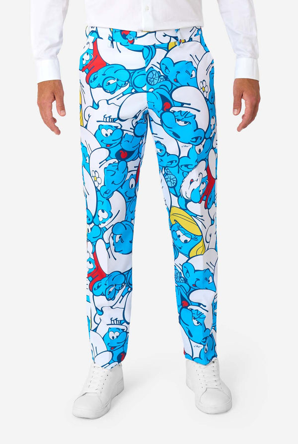 Mann trägt einen farbenfrohen Schlümpfe-Herrenanzug mit durchgehendem Cartoon-Print in Blau, Weiß, Rot und Gelb, inklusive passender Krawatte und weißem Hemd, stehend vor einem schlichten Hintergrund. Nahaufnahme der Hose.