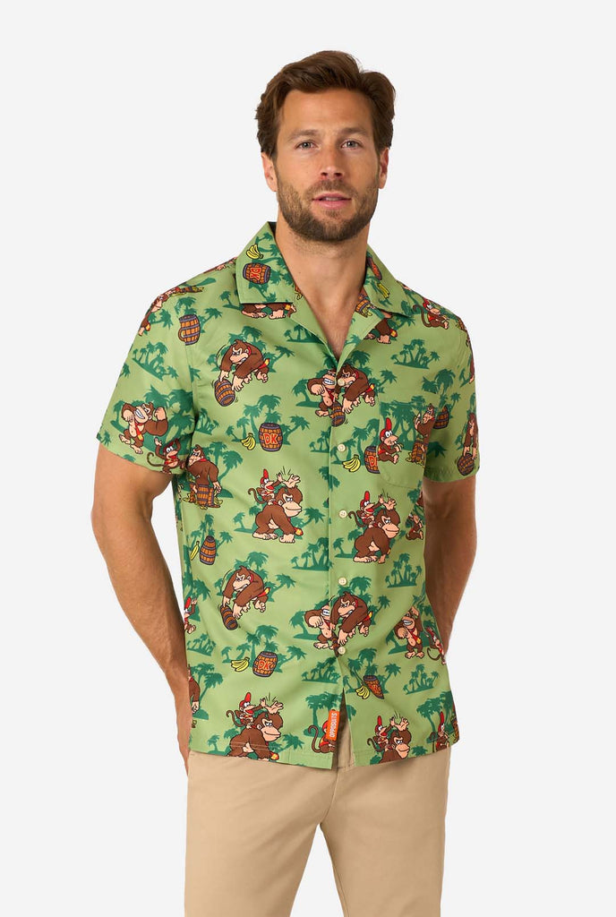 Bild eines Mannes, der ein Hawaiihemd mit Donkey-Kong-Motiv trägt. Das T-Shirt hat einen hellgrünen Hintergrund und enthält dunkelgrüne Palmen sowie mehrere Bilder der Figur Donkey Kong aus Super Mario. Der Mann blickt in die Kamera.