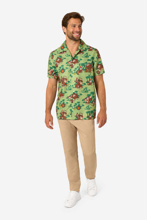 Bild eines Mannes, der ein Hawaiihemd mit Donkey-Kong-Motiv trägt. Das T-Shirt hat einen hellgrünen Hintergrund und enthält dunkelgrüne Palmen sowie mehrere Bilder der Figur Donkey Kong aus Super Mario. Der Mann blickt zur Seite, Ganzkörperbild.