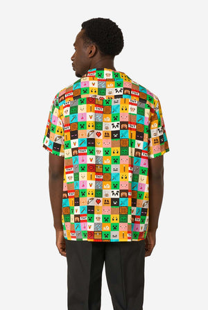 Mann, der ein farbenfrohes Minecraft-Hawaiihemd mit pixeligen Blöcken, Charakteren und Gegenständen aus dem Spiel trägt, gepaart mit einer schwarzen Hose, steht vor einem schlichten weißen Hintergrund. Ansicht von hinten