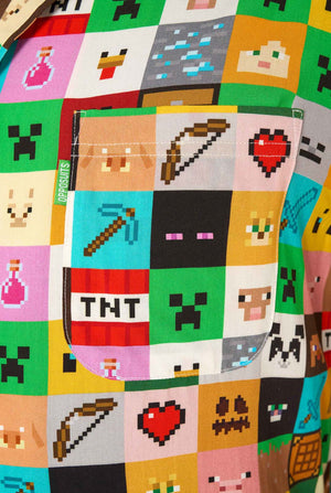 Mann, der ein farbenfrohes Minecraft-Hawaiihemd mit pixeligen Blöcken, Charakteren und Gegenständen aus dem Spiel trägt, gepaart mit einer schwarzen Hose, steht vor einem schlichten weißen Hintergrund. Nahaufnahme der Brusttasche
