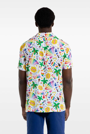 Ein Mann trägt ein weißes Hawaii-Hemd mit einem Regenbogen-Pride-Aufdruck. Der Aufdruck besteht aus Friedenssymbolen, Herzen und anderen Symbolen. Er trägt außerdem eine blaue Hose. Er lächelt in die Kamera und hält sich an den Seiten des Hemdes fest. Ansicht von hinten.
