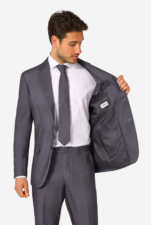 Ein Mann trägt einen stilvollen, anthrazitfarbenen Anzug mit weißem Hemd und wirkt selbstbewusst. Das perfekte formelle Outfit für besondere Anlässe, Hochzeiten und Partys.