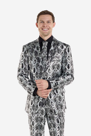 Ein Mann trägt einen auffälligen silber-schwarzen Anzug mit Schlangenmuster von OppoSuits. Der auffällige Anzug mit seinem markanten Schlangenhautmuster bietet einen eleganten, modischen Look, perfekt für Partys, Events oder ein gewagtes Modestatement. Der Herrenanzug wird mit einem schwarzen Hemd und einer passenden Krawatte mit Schlangenmuster kombiniert, was dem Gesamtensemble eine elegante Note verleiht. Das selbstbewusste Lächeln des Mannes und sein formelles, aber modernes Outfit strahlen eine modisch