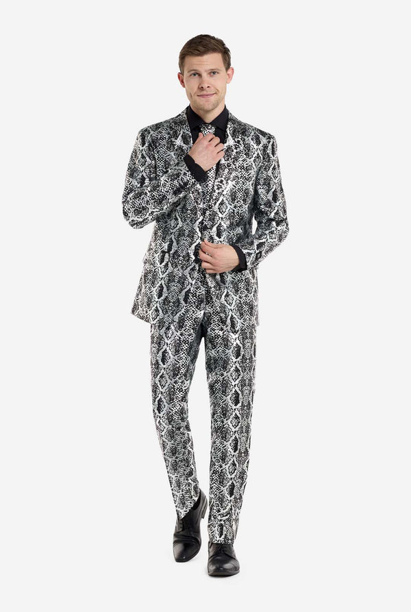 Ein Mann trägt einen auffälligen silber-schwarzen Anzug mit Schlangenmuster von OppoSuits und schwarze Schuhe. Der markante Anzug mit seinem markanten Schlangenhautmuster verleiht ihm einen eleganten, modischen Look – perfekt für Partys, Events oder ein gewagtes Modestatement. Der Herrenanzug wird mit einem schwarzen Hemd und einer passenden Krawatte mit Schlangenmuster kombiniert, was dem Gesamtensemble eine elegante Note verleiht. Das selbstbewusste Lächeln des Mannes und sein formelles, aber modernes Out