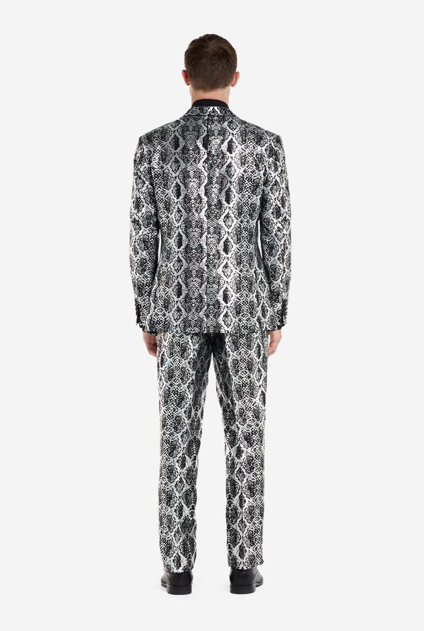 Ein Mann trägt einen auffälligen silber-schwarzen Anzug mit Schlangenmuster von OppoSuits. Der auffällige Anzug mit seinem markanten Schlangenhautmuster bietet einen eleganten, modischen Look, perfekt für Partys, Events oder ein gewagtes Modestatement. Der Herrenanzug wird mit einem schwarzen Hemd und einer passenden Krawatte mit Schlangenmuster kombiniert, was dem Gesamtensemble eine elegante Note verleiht. Ansicht von hinten.