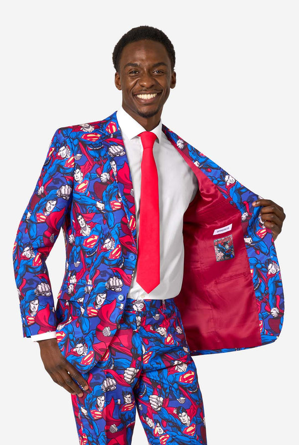 Ein Mann im Superman-Anzug mit roter Krawatte und weißem Hemd auf weißem Hintergrund. Hält seine Jacke offen