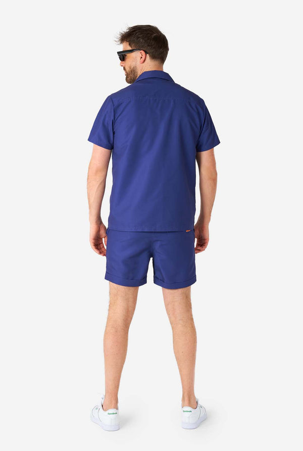 Mann trägt blaues Sommerset bestehend aus Hemd und Shorts, Ganzkörperansicht von hinten
