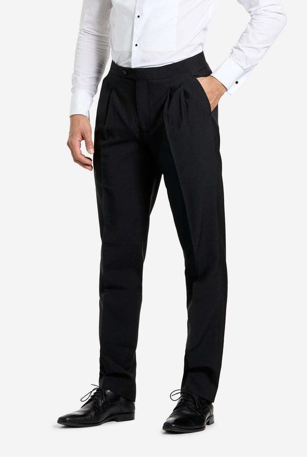 Mann, der einen holographischen silbernen Paillettentuxedo mit schwarzen Satin -Repfels trägt, gepaart mit einem weißen Hemd, einer schwarzen Fliege und einer schwarzen Hose.