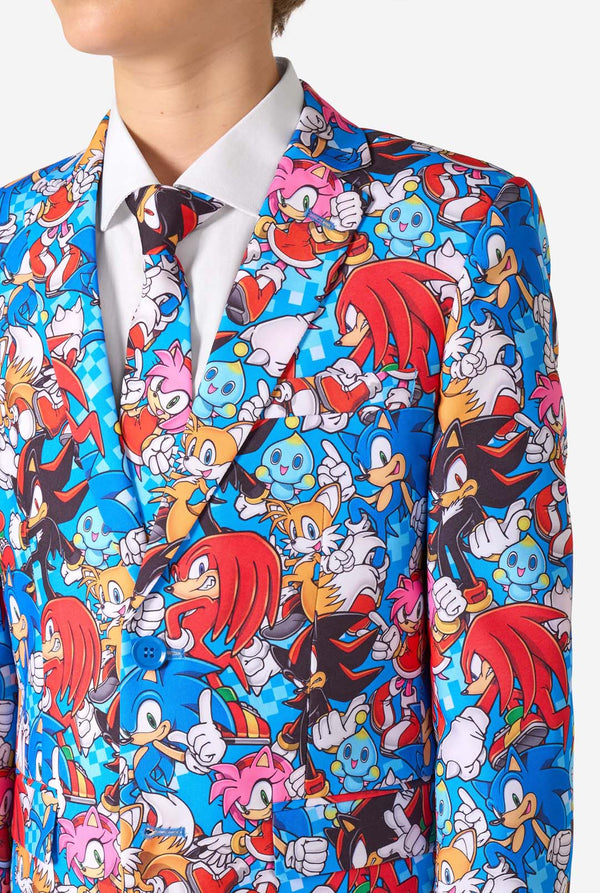 Teenager trägt einen farbenfrohen Sonic-Teenie-Anzug mit bunten Aufdrucken von Sonic the Hedgehog-Figuren wie Sonic, Knuckles, Tails und Amy, gepaart mit einer passenden Krawatte und einem weißen Hemd. Nahaufnahme der Brust.