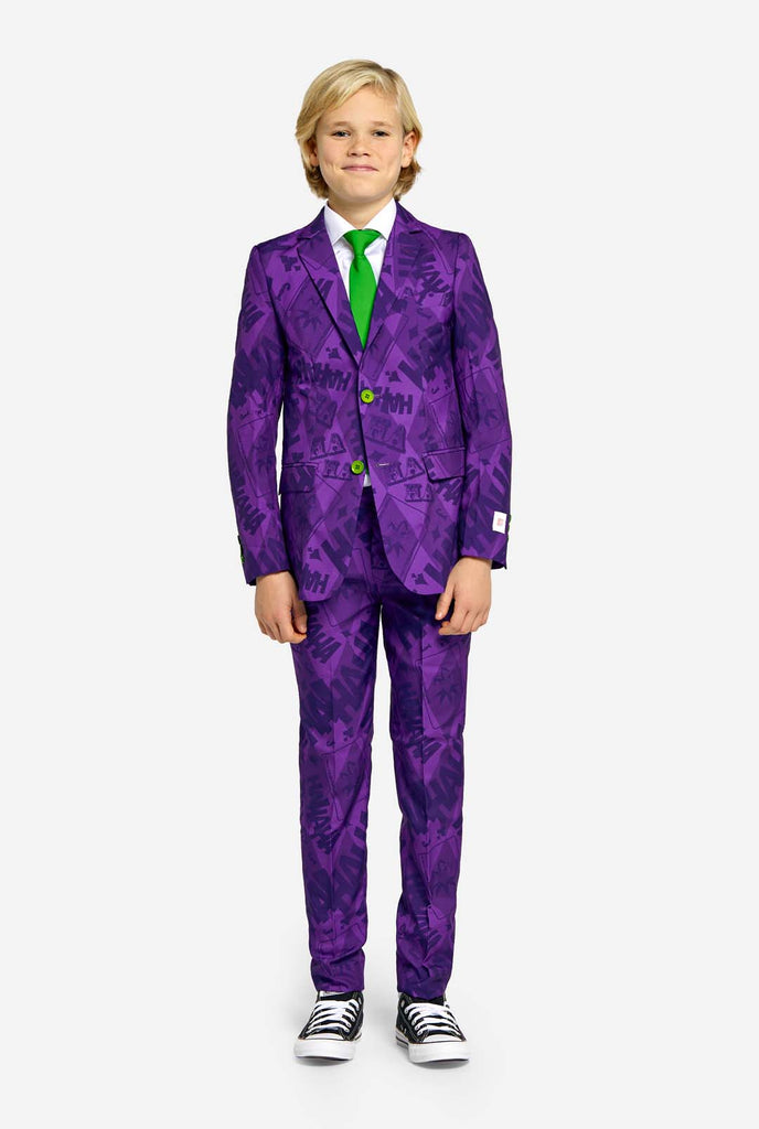 Teenager trägt einen lilafarbenen Jungenanzug mit Joker-Motiv und grünen Knöpfen. Außerdem trägt er eine grüne Krawatte und ein weißes Hemd.