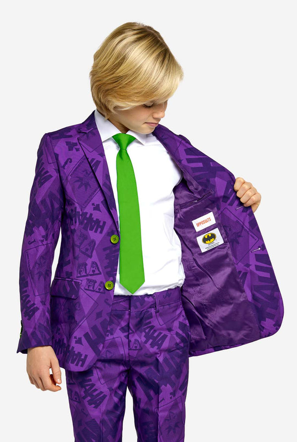 Teenager trägt einen lilafarbenen Jungenanzug mit Joker-Motiv und grünen Knöpfen. Außerdem trägt er eine grüne Krawatte und ein weißes Hemd.