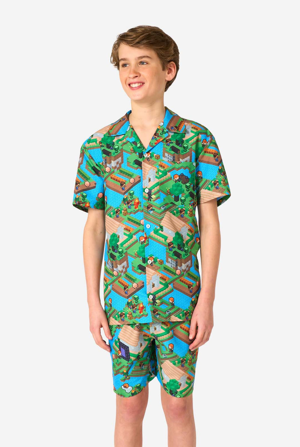 Ein Teenager-Junge trägt ein buntes Sommeroutfit mit einem Minecraft-Overworld-Motiv, das pixelige Landschaften, Charaktere und Elemente aus dem ikonischen Spiel zeigt. Das kurzärmelige Hemd und die passenden Shorts heben ein lebhaftes Design hervor, das von der Minecraft-Welt inspiriert ist.