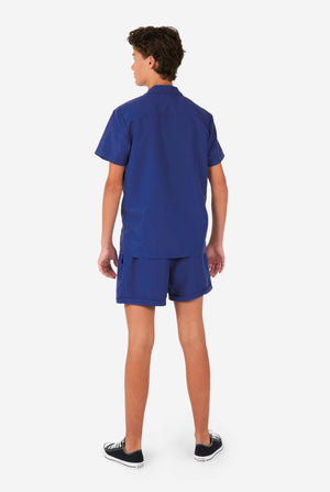 Junge trägt dunkelblaues Sommerset, bestehend aus Shorts und Hemd, Blick von hinten