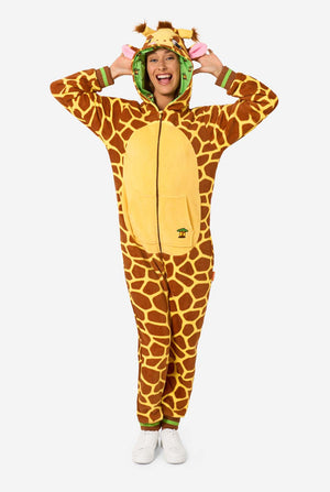 Eine lächelnde Frau trägt einen braunen und gelben Strampler für Erwachsene in Form einer Giraffe. Der Strampler hat eine Kapuze, die einem Giraffenkopf ähnelt, und Giraffendetails, perfekt zum gemütlichen Faulenzen oder für Kostümpartys. 