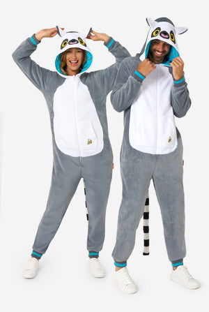 Ein Mann und eine Frau tragen einen grau-weißen Lemur-Onesie für Erwachsene mit verspielten Kapuzendetails und kuschelig weichem Material, perfekt zum Faulenzen oder für Kostümveranstaltungen. Mit schwarzem und weißem Schwanz. Die Kapuze haben sie auf dem Kopf. Ganzkörperbild.