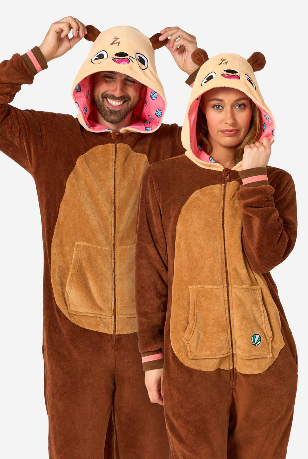 Ein lächelnder Mann und eine Frau tragen braune Erwachsenen-Onesies, die als Otter gestaltet sind. Der Onesie verfügt über eine Kapuze mit Ohren, ein niedliches Gesicht und verspielte Otter-Details, perfekt zum gemütlichen Entspannen oder für Kostümpartys.