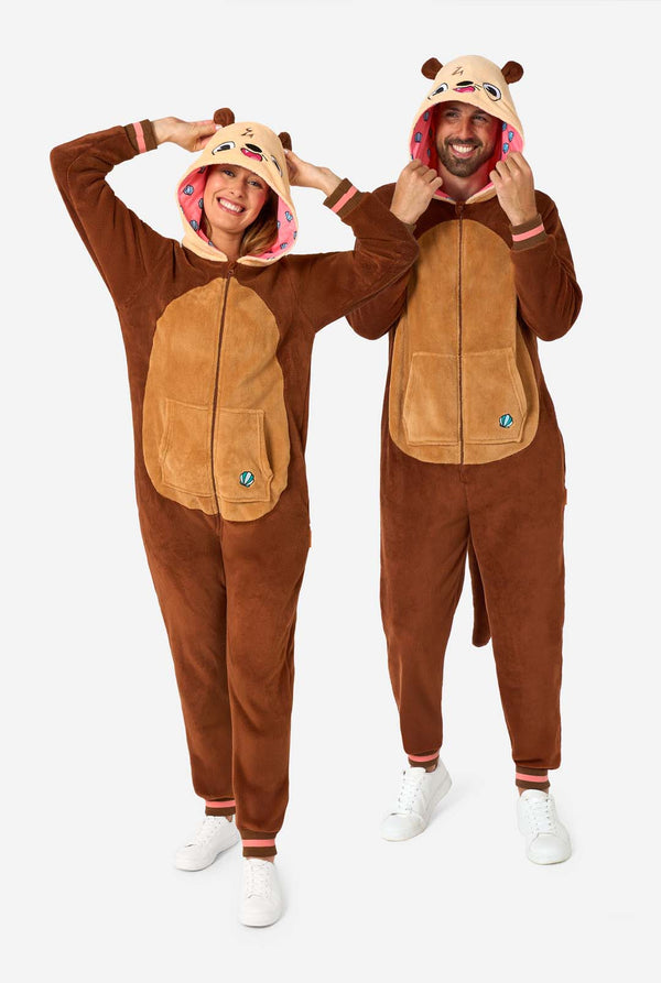 Ein lächelnder Mann und eine lächelnde Frau tragen braune Erwachsenen-Onesies, die als Otter gestaltet sind. Der Onesie verfügt über eine Kapuze mit Ohren, ein niedliches Gesicht und verspielte Otter-Details, perfekt zum gemütlichen Entspannen oder für Kostümpartys. Ganzkörperaufnahme.