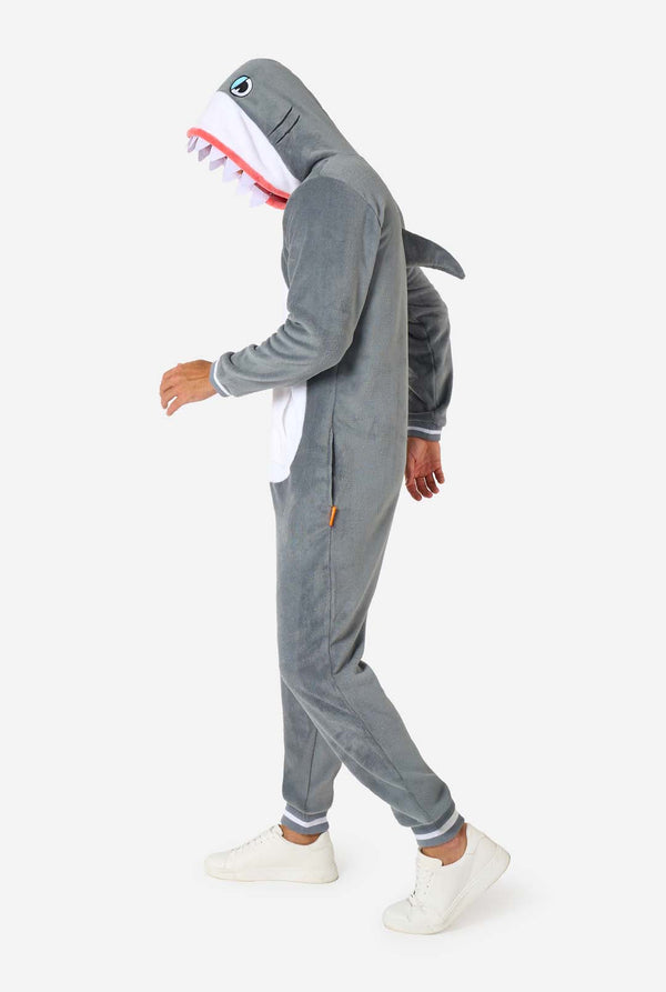 Ein Mann trägt einen grau-weißen Hai-Onesie für Erwachsene mit verspielten Kapuzendetails und kuscheligem, weichem Material, perfekt zum Entspannen oder für Kostümveranstaltungen. Ganzkörperbild von der Seite.