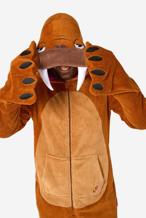 Ein fröhlicher Mann trägt einen braunen Erwachsenen-Onesie in Walross-Optik. Der Onesie hat eine Kapuze mit Reißzähnen, aufgenähte Handschuhe in Pfotenform und verspielte Walross-Details – perfekt für gemütliches Faulenzen oder Kostümpartys. Nahaufnahme des Oberkörpers.