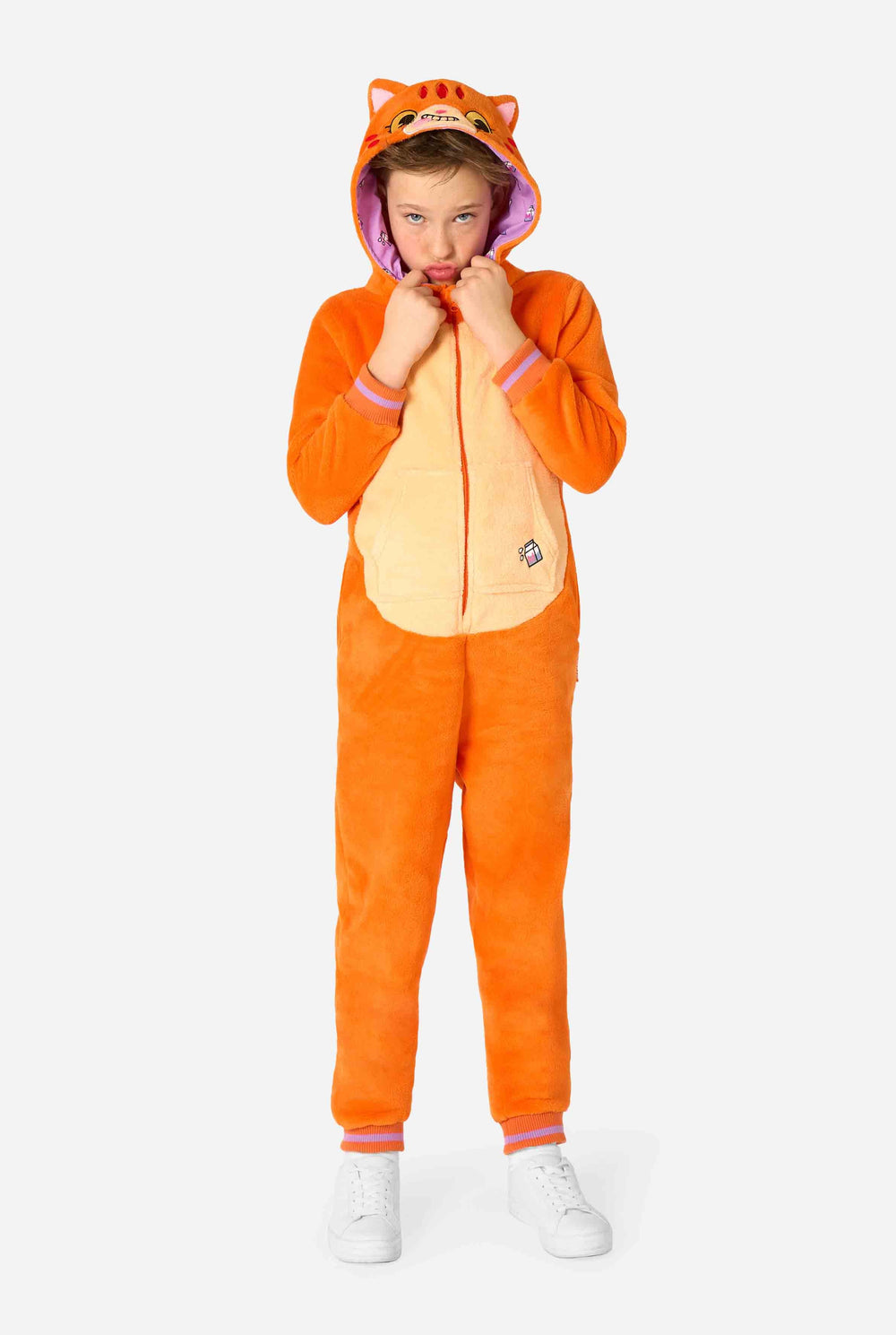 Kind trägt einen verspielten, unisex Kinder-Onesie im Design einer rot-orangefarbenen Katze, mit Kapuze, die ein Cartoon-Katzengesicht und Ohren zeigt, sowie einem hellbeigen Bauchpaneel. Das Kind zieht eine lustige Grimasse vor einem schlichten Hintergrund.