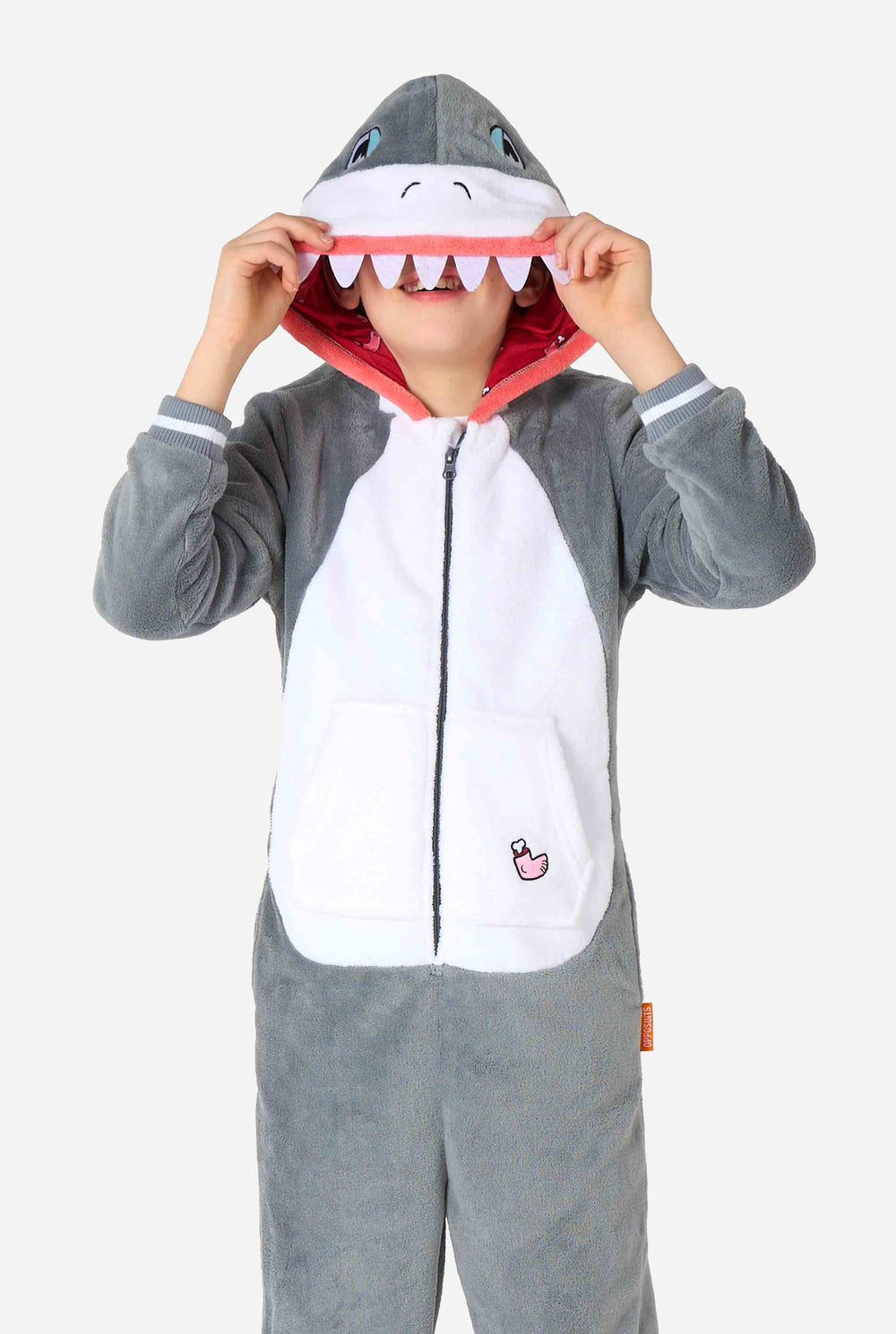 Ein Kind trägt einen grau-weißen Hai-Einteiler für Kinder mit verspielten Kapuzendetails und kuscheligem, weichem Material, perfekt zum Faulenzen oder für Kostümveranstaltungen.