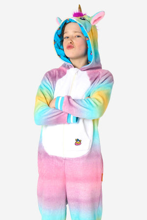 Ein lächelndes Kind trägt einen weißen, rosa, blauen und gelben Kinderstrampler, der als Einhorn gestaltet ist. Der Einhorn-Einteiler verfügt über eine Kapuze, die einem Einhornkopf ähnelt, und weitere verspielte Details