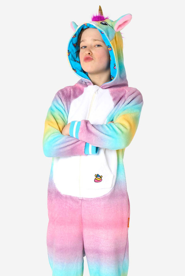 Ein lächelndes Kind trägt einen weißen, rosa, blauen und gelben Kinderstrampler, der als Einhorn gestaltet ist. Der Einhorn-Einteiler verfügt über eine Kapuze, die einem Einhornkopf ähnelt, und weitere verspielte Details