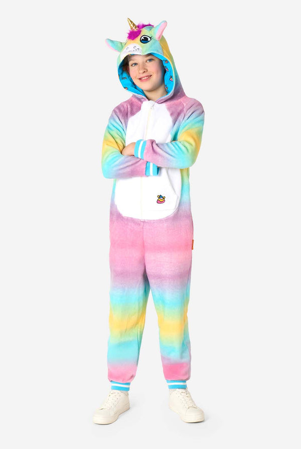 Ein lächelndes Kind trägt einen weißen, rosa, blauen und gelben Kinderstrampler, der als Einhorn gestaltet ist. Der Einhorn-Einteiler verfügt über eine Kapuze, die einem Einhornkopf ähnelt, und weitere verspielte Details. Ganzkörperbild.