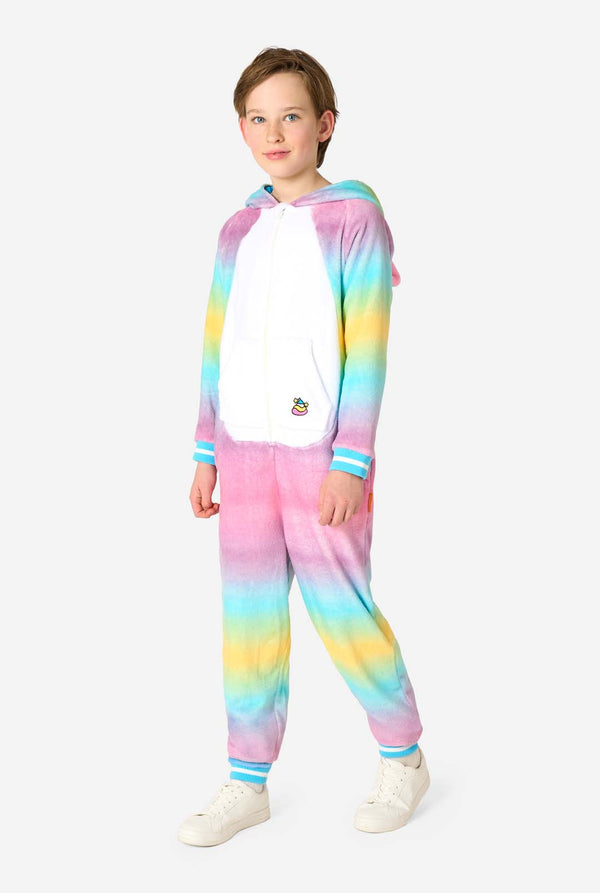 Ein lächelndes Kind trägt einen weißen, rosa, blauen und gelben Kinderstrampler, der als Einhorn gestaltet ist. Der Einhorn-Einteiler verfügt über eine Kapuze, die einem Einhornkopf ähnelt, und weitere verspielte Details. Ganzkörperbild mit heruntergelassener Kapuze.