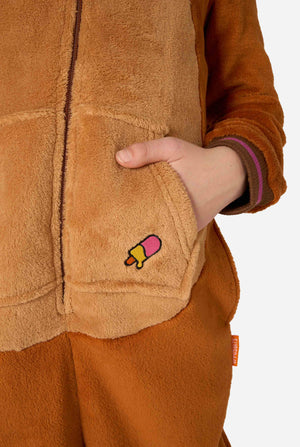 Ein fröhliches Kind trägt einen braunen Kinder-Onesie in Walross-Optik. Der Onesie hat eine Kapuze mit Reißzähnen, aufgenähte Handschuhe in Pfotenform und verspielte Walross-Details – perfekt für gemütliches Faulenzen oder Kostümpartys. Nahaufnahme.